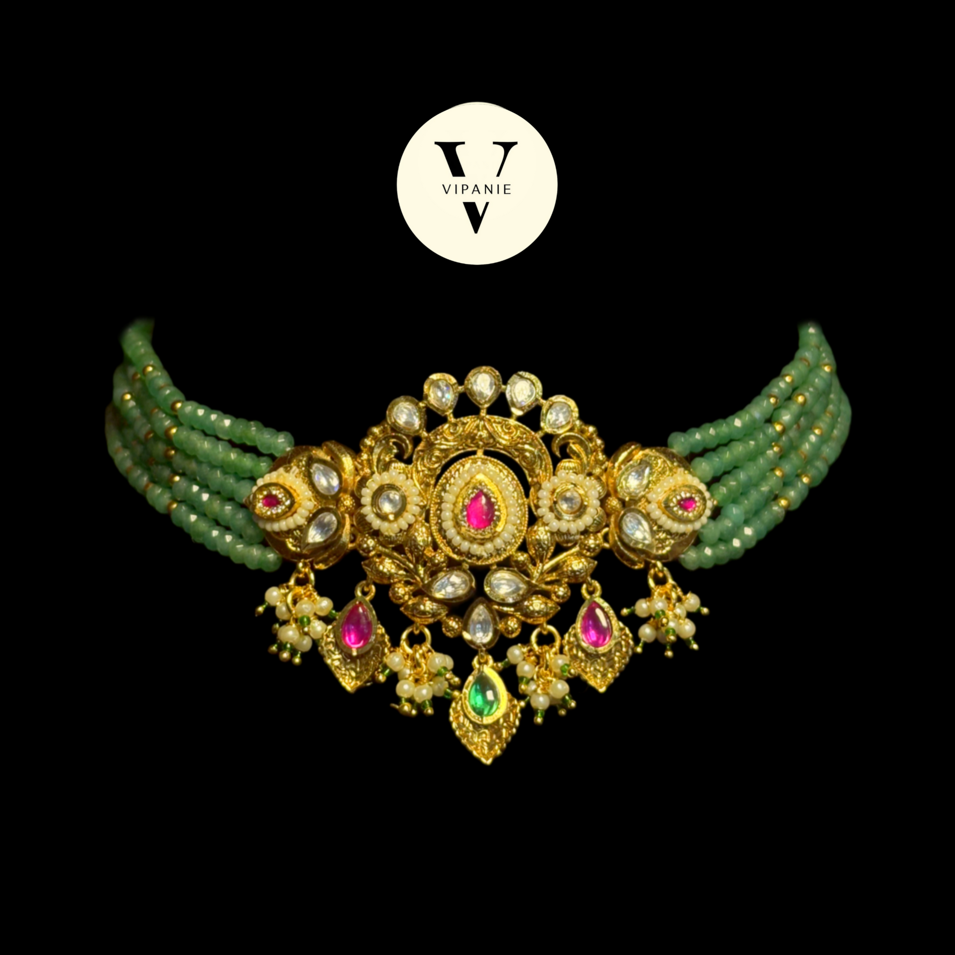 An ornate gold-plated choker necklace with green beaded strands, white faux pearls, and pink and green gemstone accents, displayed on a solid black background with a white Vipanie logo above.